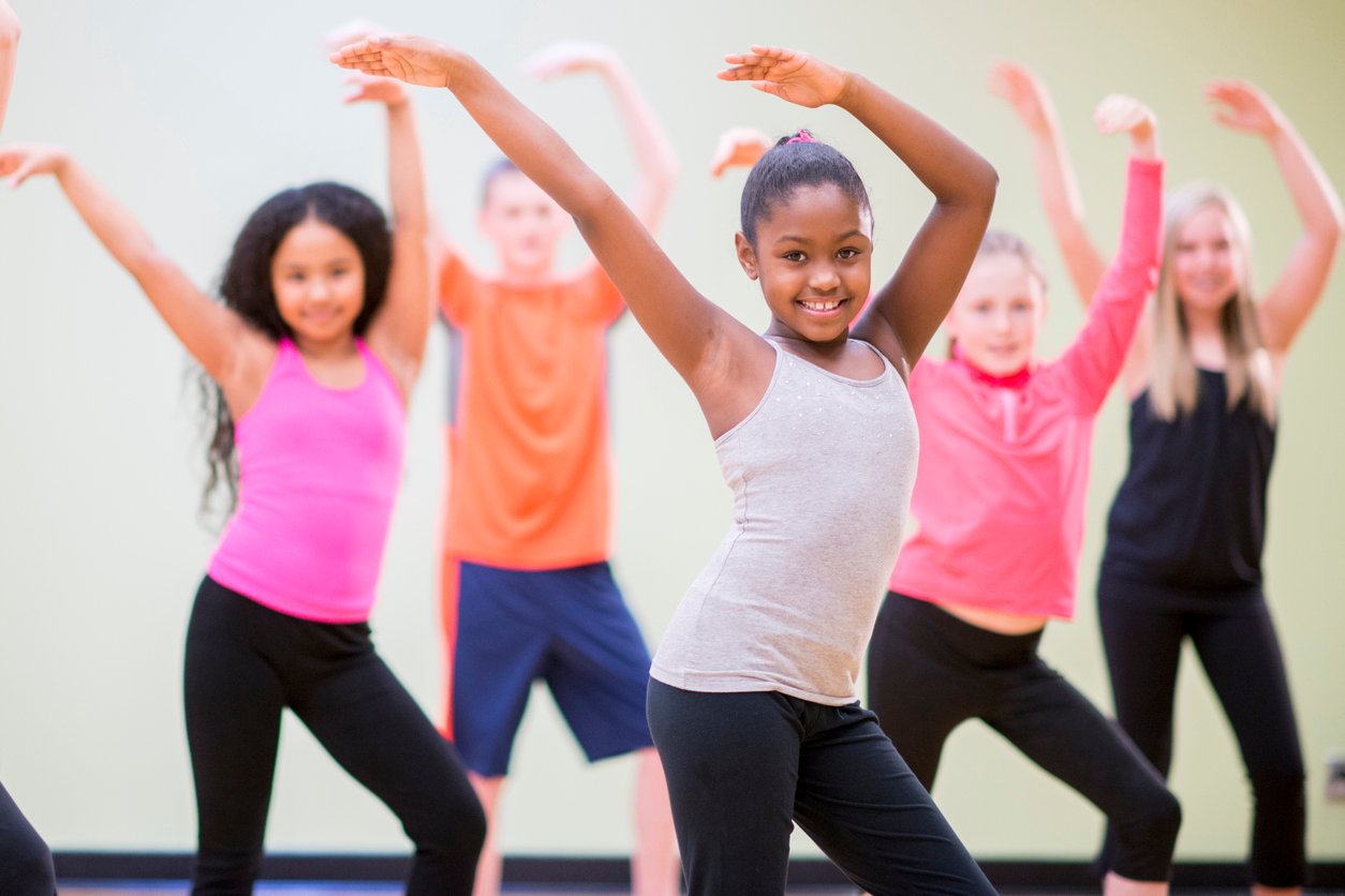 A diverse group of children learning choreography in a dance class.